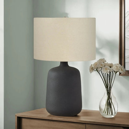 Table lamp with black matte ceramic base and beige fabric shade on wooden dresser on Tampa Home & Garden Store
