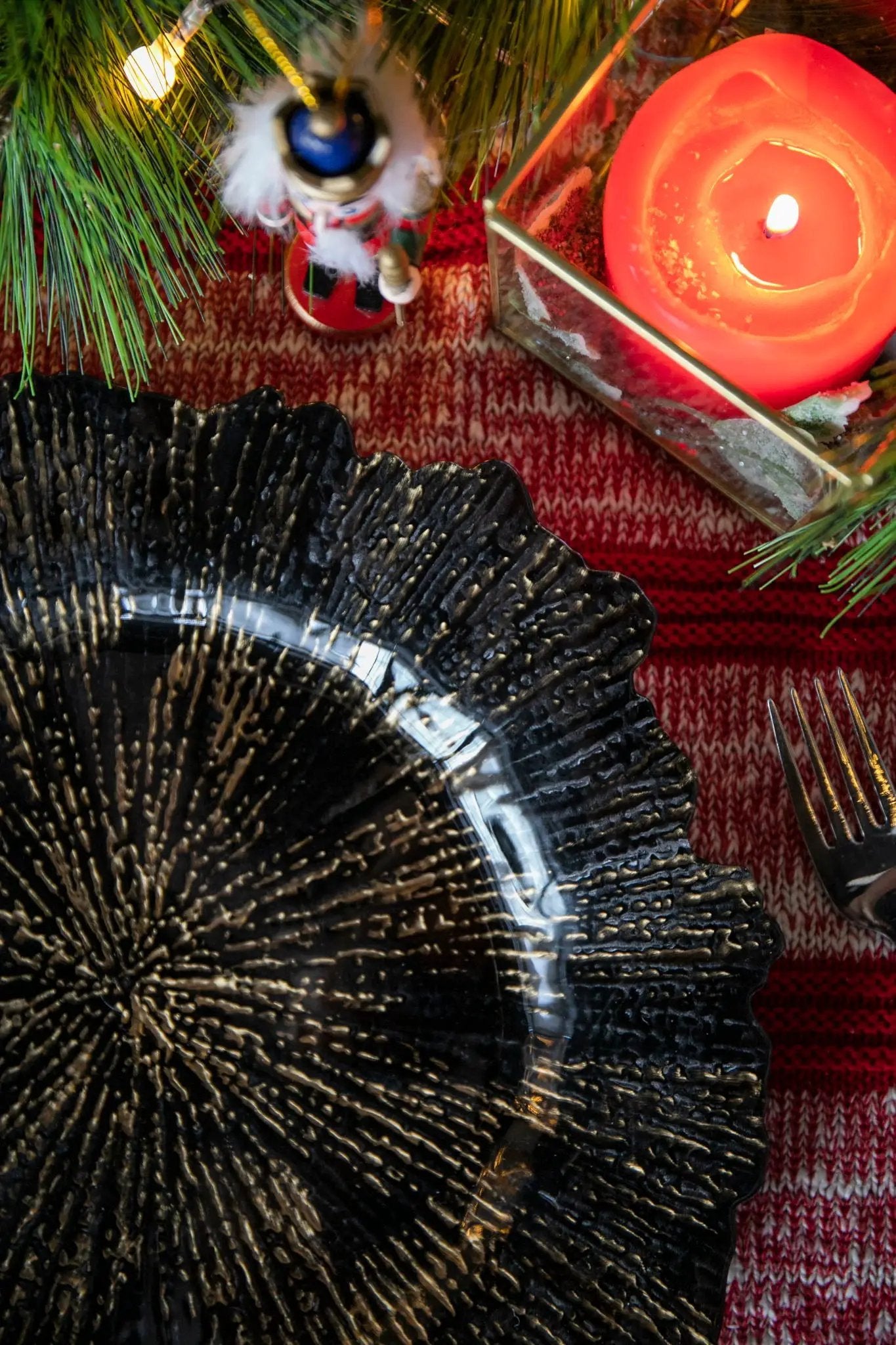 Plastic charger plate set of 8, black textured starburst design on a festive red table with candle on Tampa Home & Garden Store