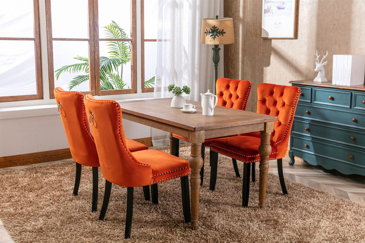 Tufted velvet orange dining chairs set of four with nailhead trim and black legs around a wood table on Tampa Home & Garden Store
