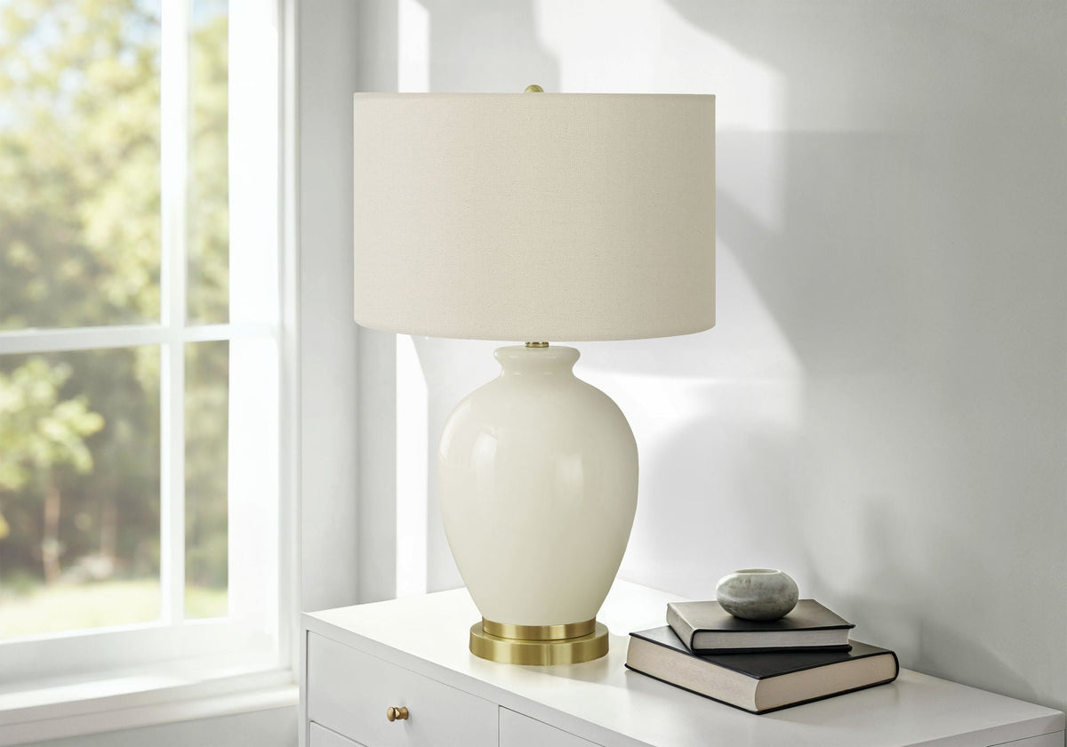 Transitional cream ceramic table lamp with beige linen shade and brass base on white dresser on Tampa Home & Garden Store