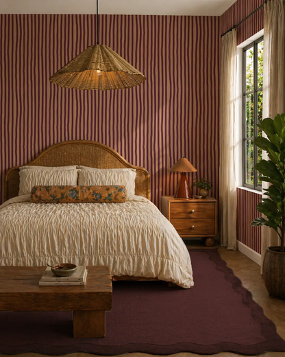 Dolce Stripe Wallpaper peach and eggplant in a cozy bedroom with rattan headboard on Tampa Home & Garden Store