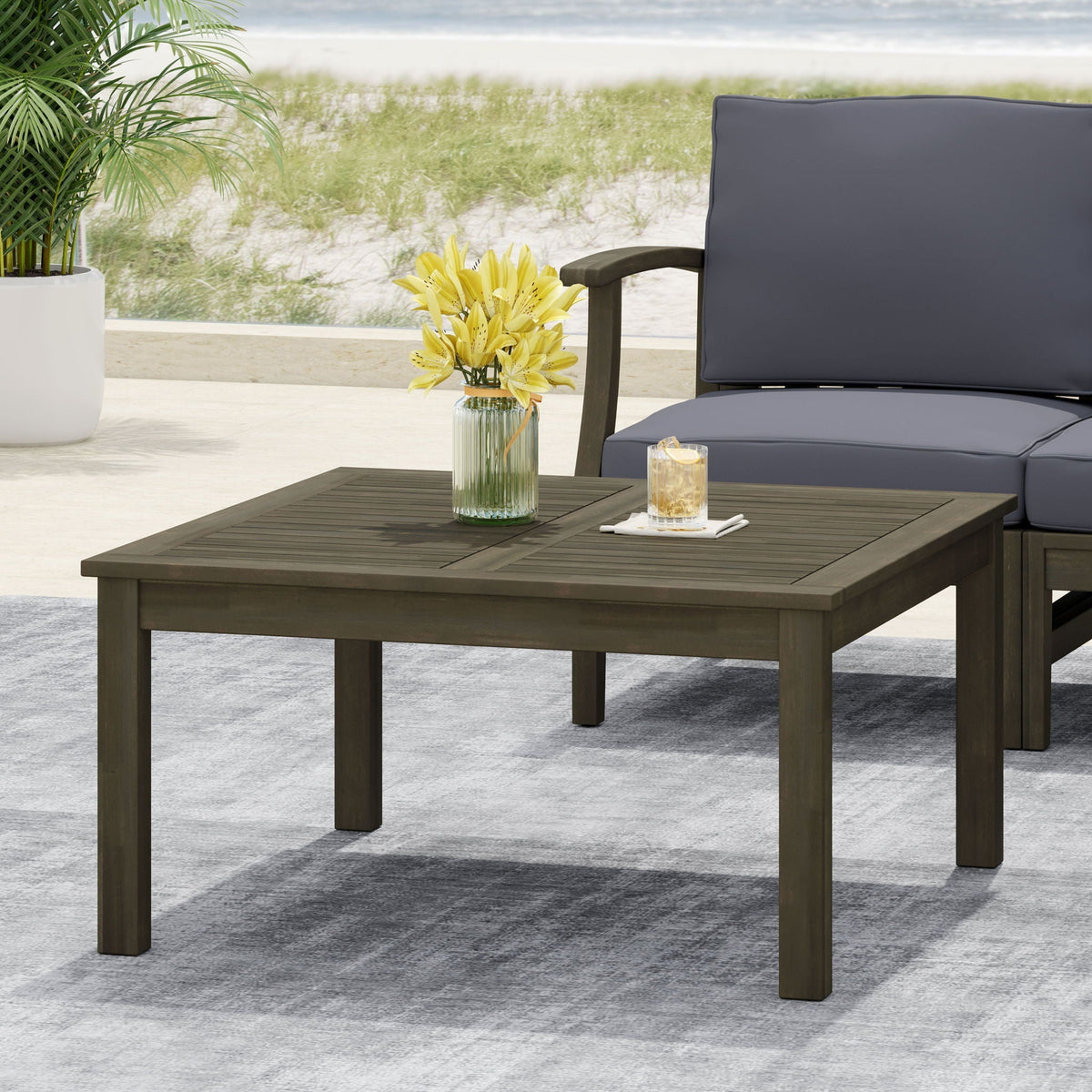 Perla Rustic Square Coffee Table with Block Legs brown-gray finish on patio with cushions on Tampa Home & Garden Store