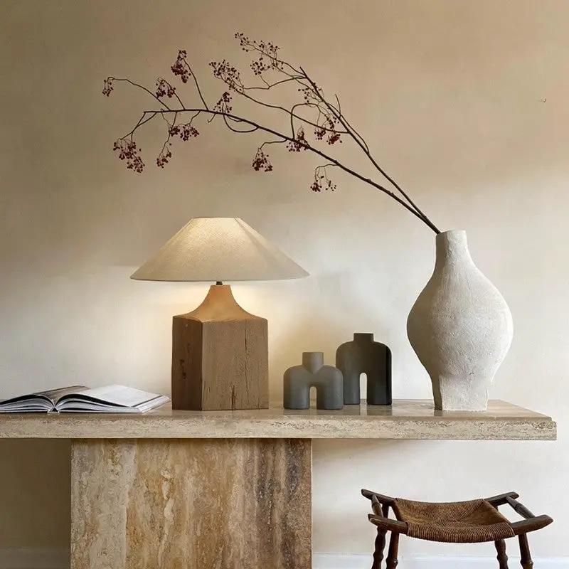 Solid wood table lamp with beige shade on a stone console, four vases and an open book on Tampa Home & Garden Store