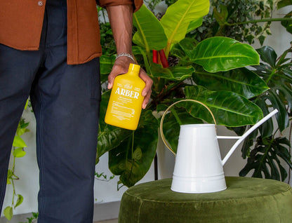Organic Bio Insecticide bottle by Rooted Treasures Farms beside a watering can on Tampa Home & Garden Store