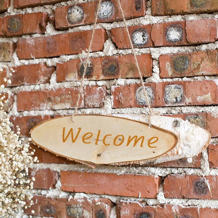 Birch Wood Solid Wood Sign Board, oval Welcome sign hung by jute twine on brick wall on Tampa Home & Garden Store