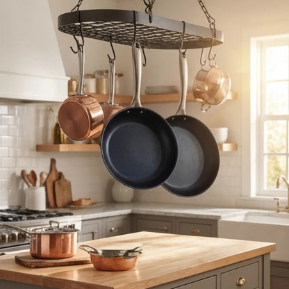 Alva Cookware carbon steel frying pans, two black pans hanging from ceiling rack in bright kitchen on Tampa Home & Garden Store