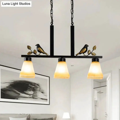 Ornate black and gold island light pendant with 3 tan glass shades and bird accents on a bar on Tampa Home & Garden Store