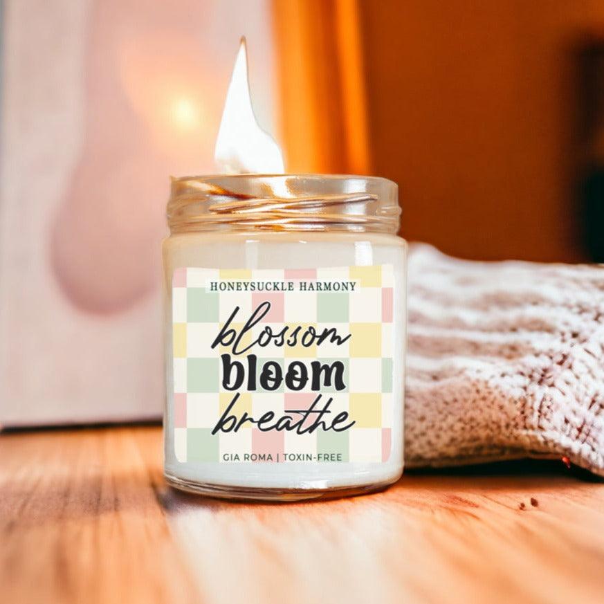 Honeysuckle Harmony Candle in a clear glass jar with pastel gingham label by Gia Roma, lit on Tampa Home & Garden Store
