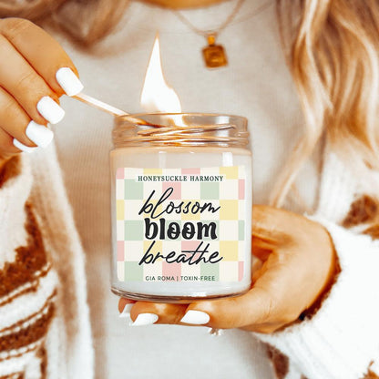 Honeysuckle Harmony Candle Gia Roma in clear jar with pastel check label, lit by a match on Tampa Home & Garden Store