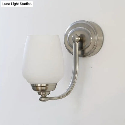 Nickel glass wall lamp sconce with curved arm and white glass shade on round backplate on Tampa Home & Garden Store