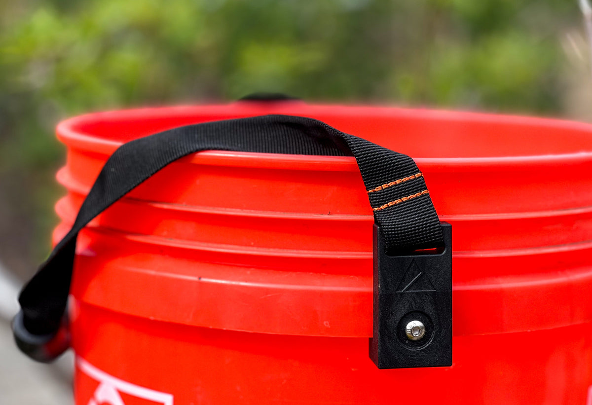 Bucket handle with black nylon strap and orange stitching on red bucket on Tampa Home & Garden Store