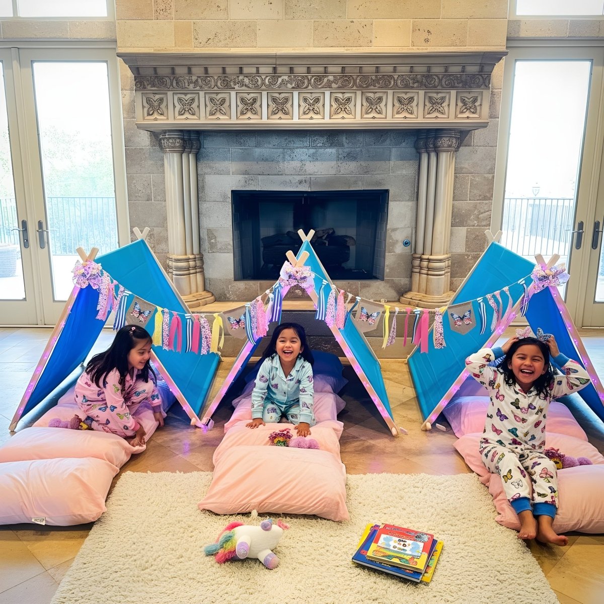 Butterfly Birthday Party Sleepover Kit: three blue tents, pink pillows, butterfly garlands; kids in pajamas at a cozy indoor campsite by the fireplace on Tampa Home & Garden Store
