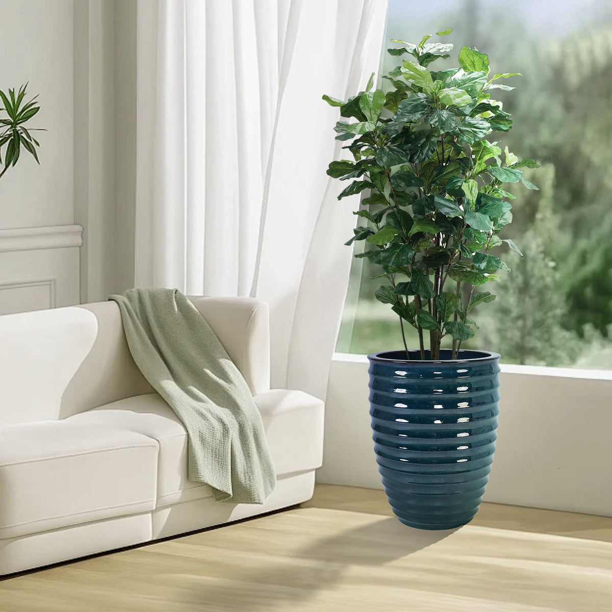 Planter blue ribbed ceramic with leafy indoor plant beside a white sofa in a bright living room on Tampa Home & Garden Store