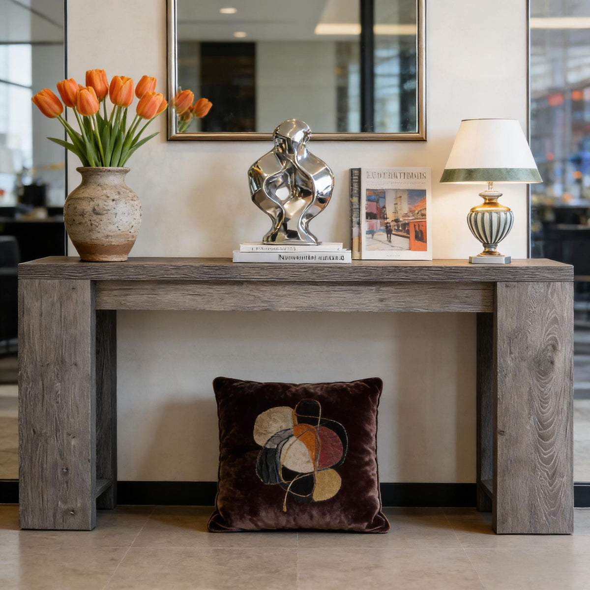 Wood entryway console table with weathered gray finish, orange tulip vase, chrome sculpture, and lamp on Tampa Home & Garden Store