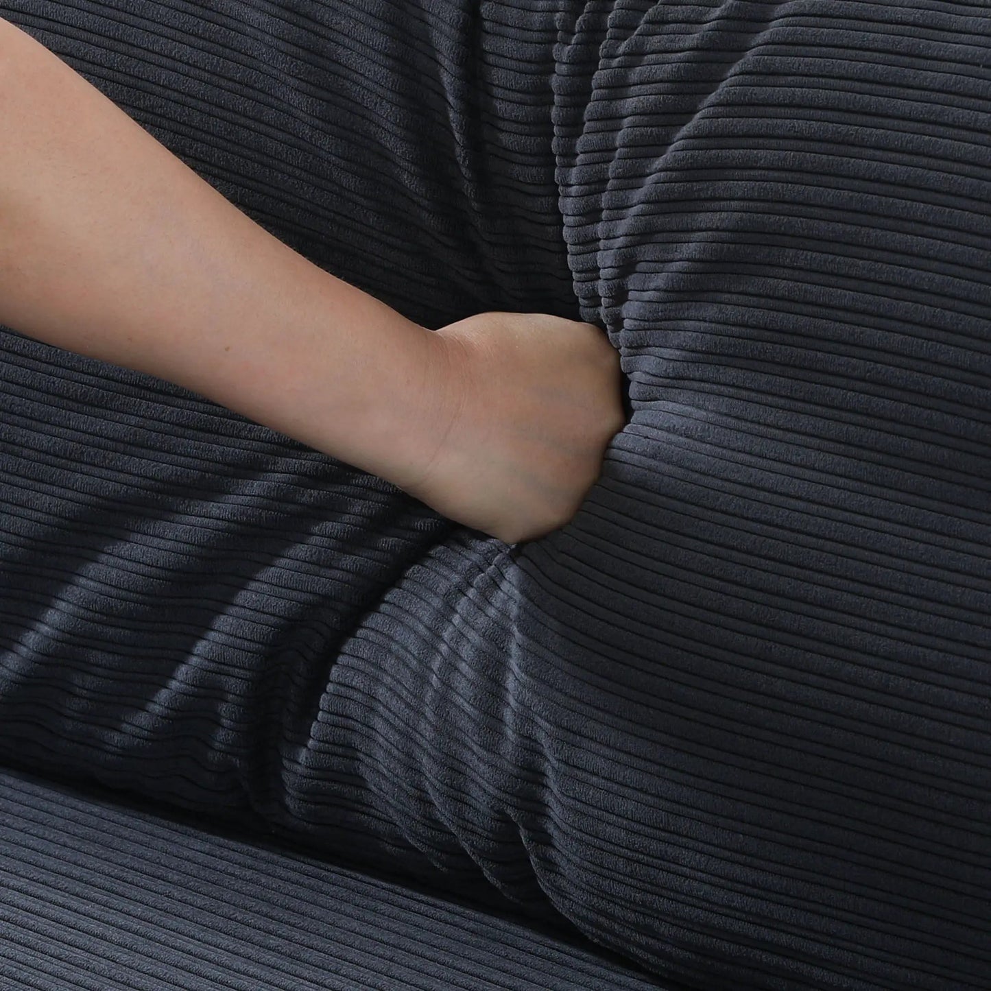 Stationary sofa upholstery close-up in navy blue ribbed velvet fabric with an arm resting on Tampa Home & Garden Store