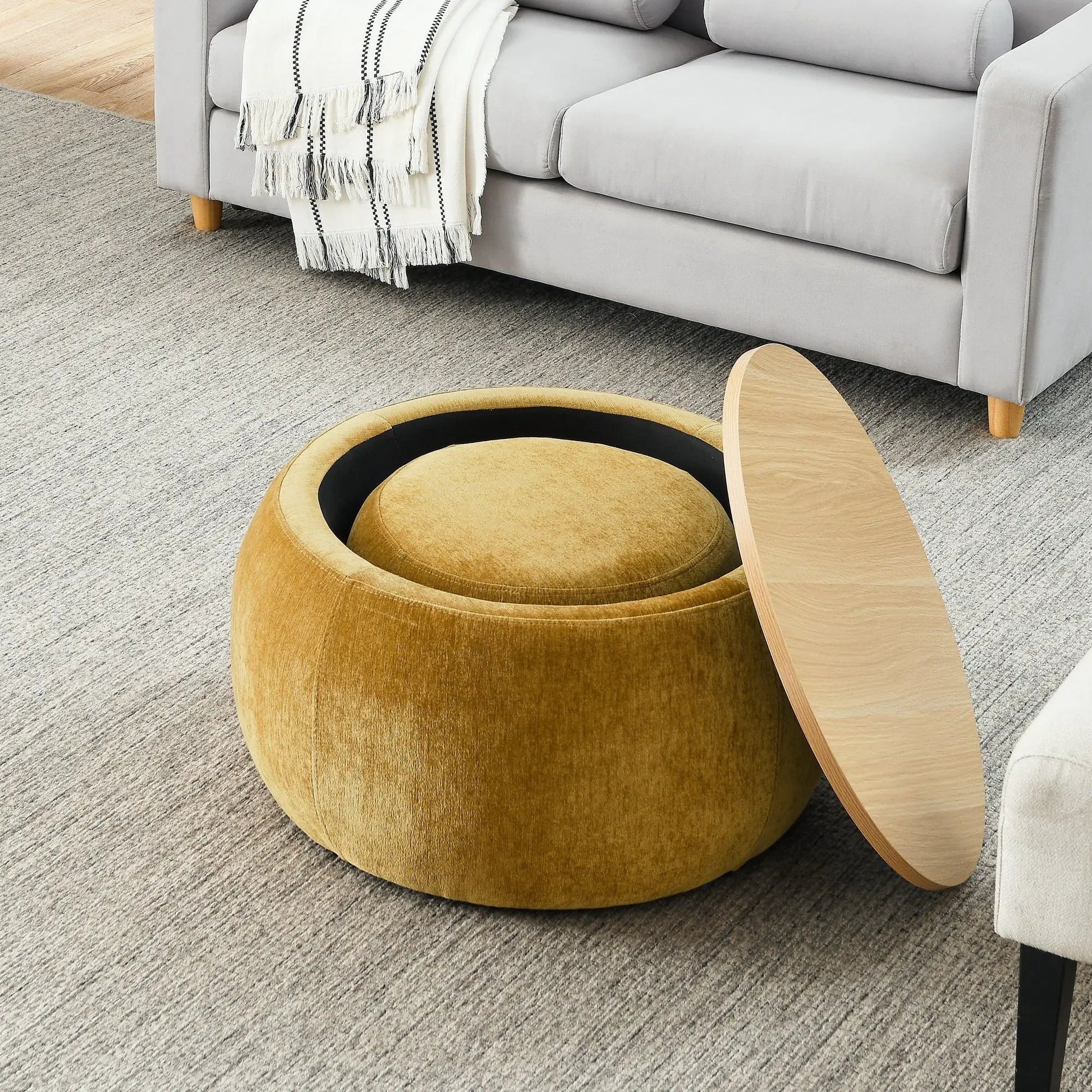 Round tan storage ottoman beside a gray sofa in a living room by Unique Piece Furniture on Tampa Home & Garden Store