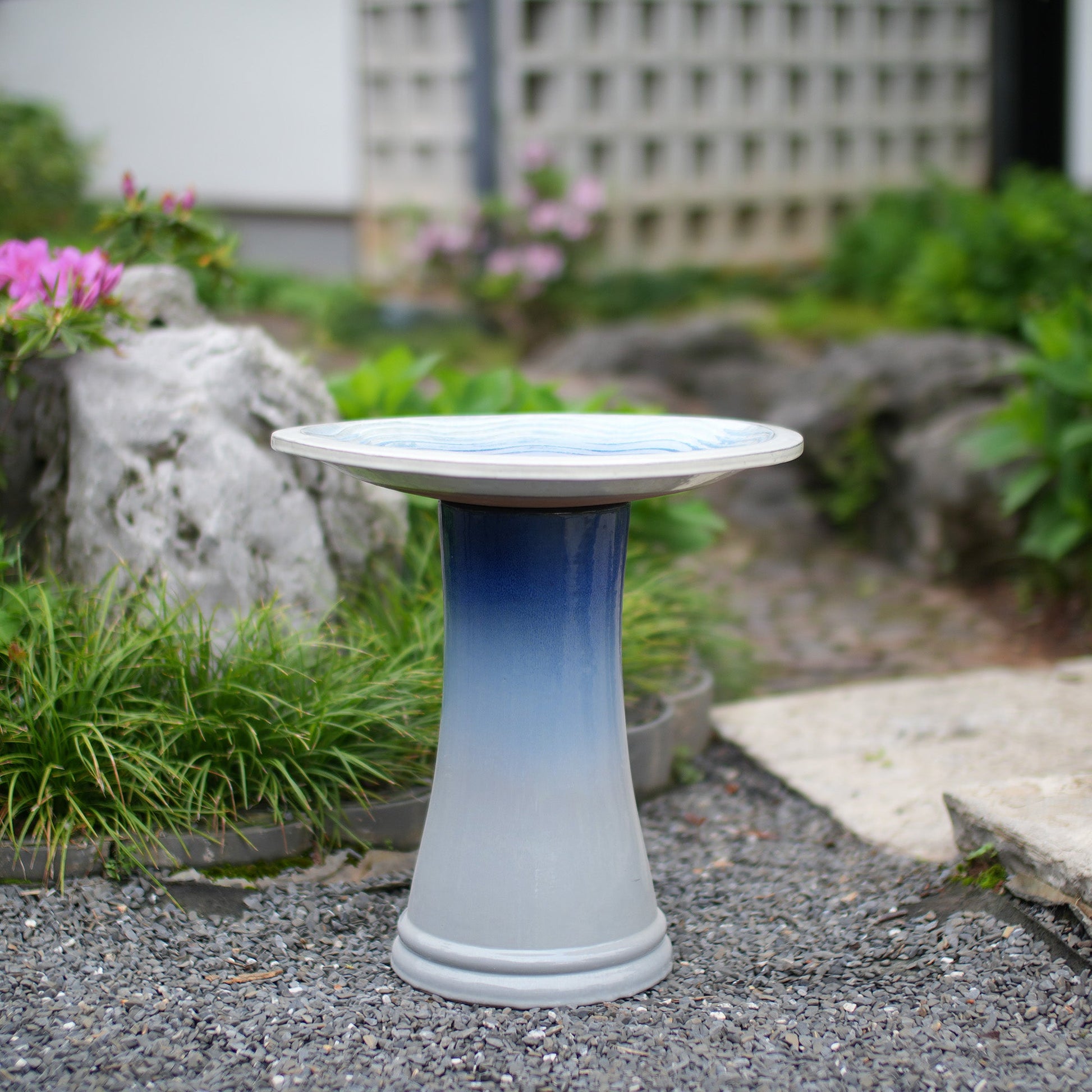 Handmade glazed ceramic bird bath on a blue gradient pedestal in a garden setting on Tampa Home & Garden Store