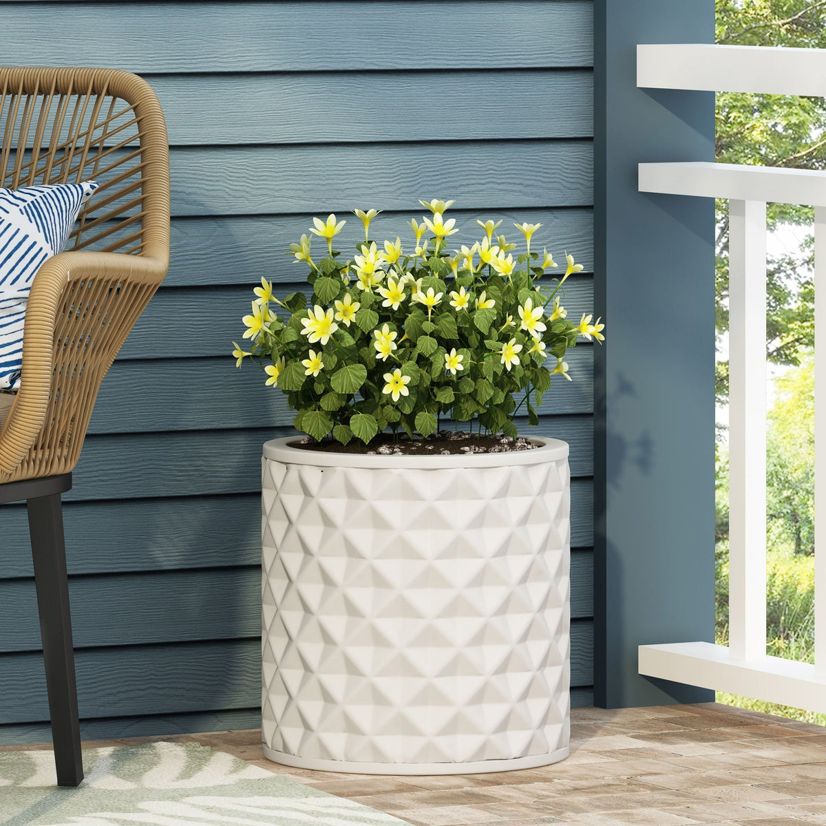 Antique white ceramic planter with geometric pattern, yellow flowers on blue siding on Tampa Home & Garden Store