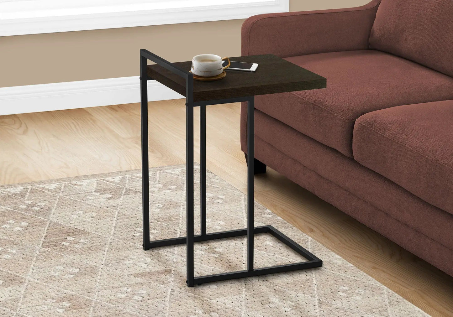 C-shaped Accent Table dark wood top, black metal frame beside sofa; cup and phone on top on Tampa Home & Garden Store