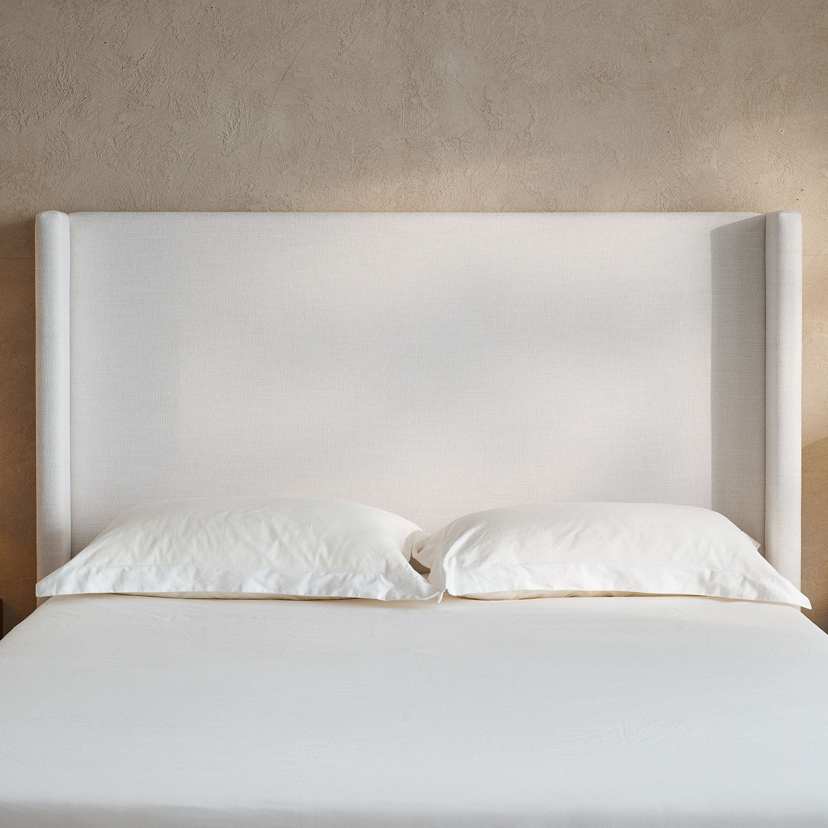 Hosford minimalist upholstered wingback bed in light beige fabric with white bedding on Tampa Home & Garden Store
