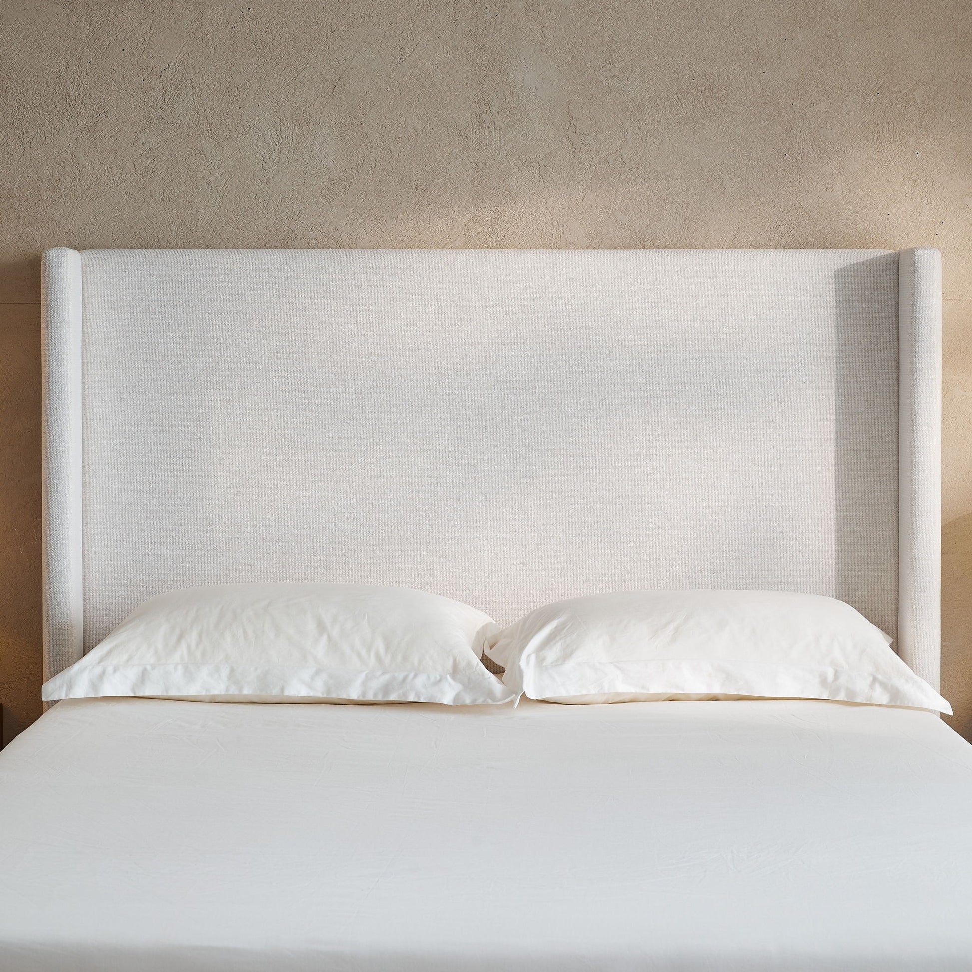 Hosford minimalist upholstered wingback bed in light beige fabric with white bedding on Tampa Home & Garden Store