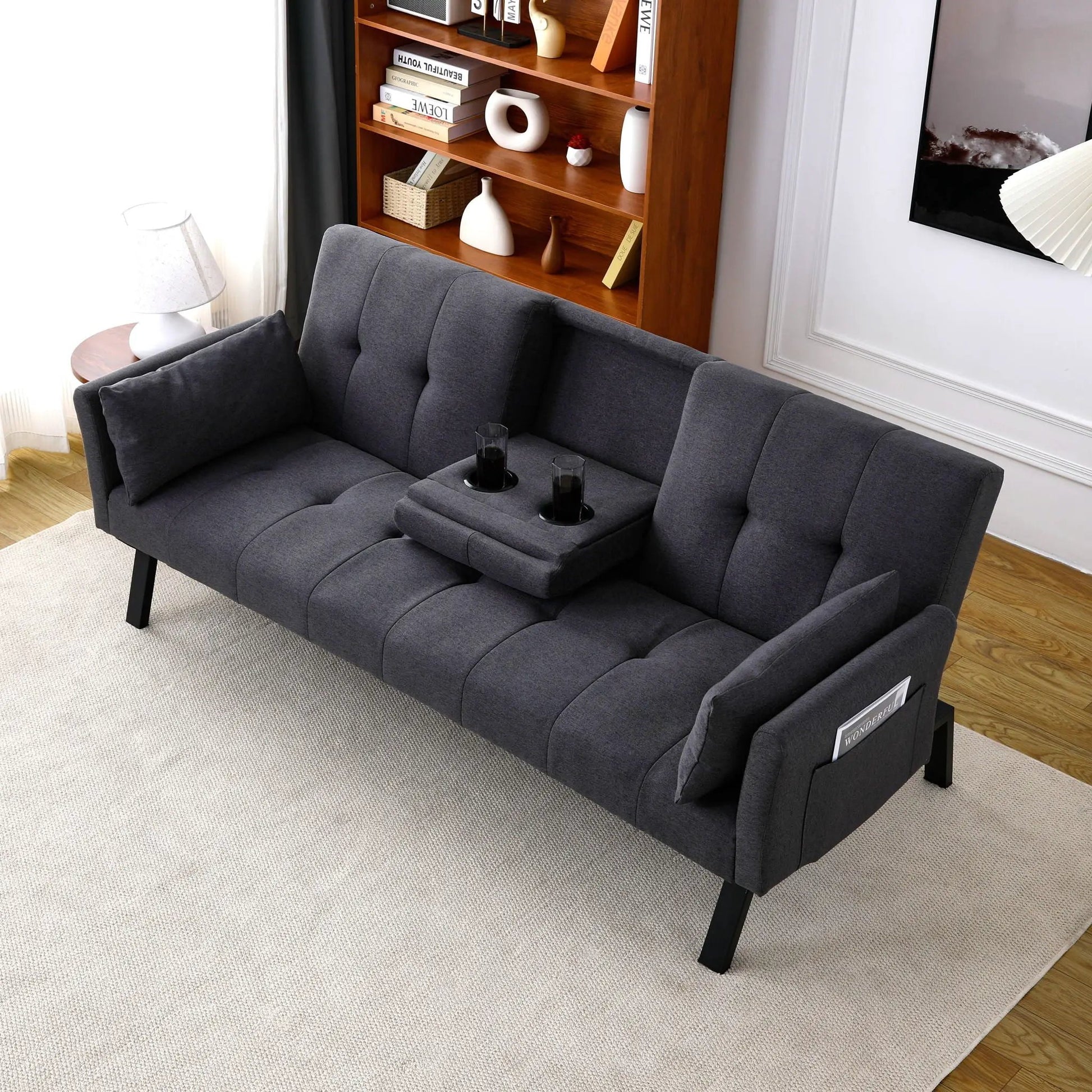 Futon sofa bed in dark gray fabric with foldable design and two cup holders on Tampa Home & Garden Store
