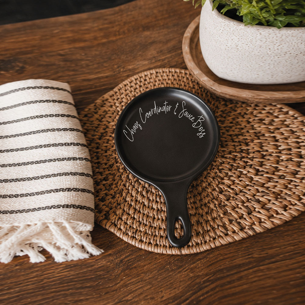 Chaos & Sauce Boss spoon rest, Gia Roma, black with white script on woven placemat on Tampa Home & Garden Store