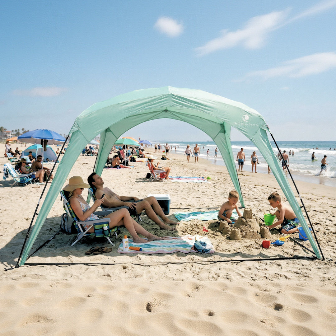 Pop 'N Go Canopy mint green beach shelter with family relaxing and kids building sandcastles on a sunny beach on Tampa Home & Garden Store