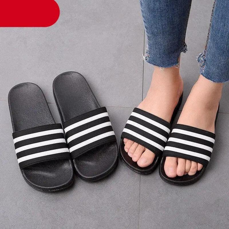 Two pairs of black and white striped slide sandals with open toe for casual summer wear on Tampa Home & Garden Store