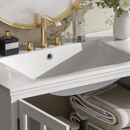 Modern white vanity with ceramic sink and gold fixtures, brass knobs, towels, and vase accents on Tampa Home & Garden Store