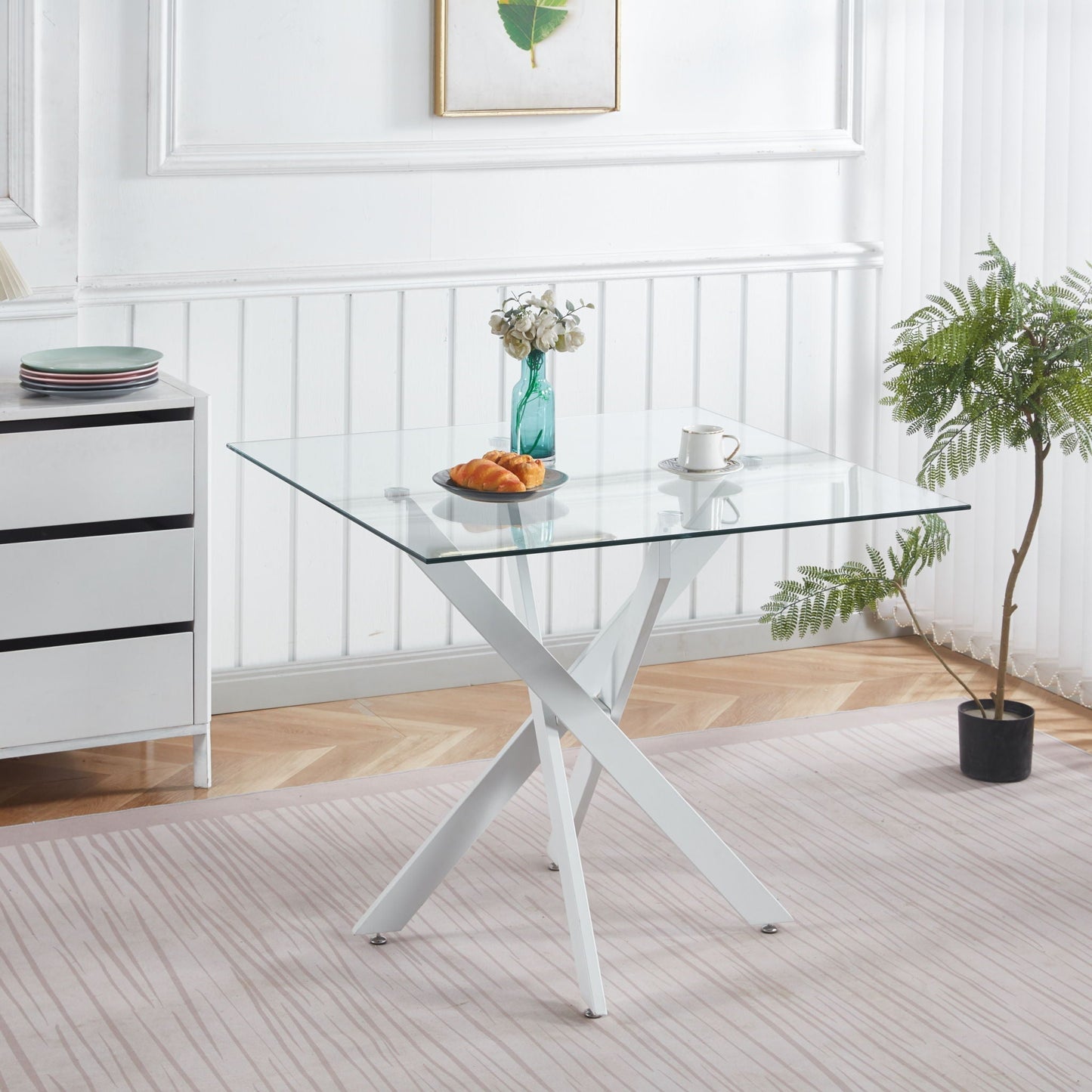 Glass dining table with cross metal legs and tempered top in a modern white dining area on Tampa Home & Garden Store