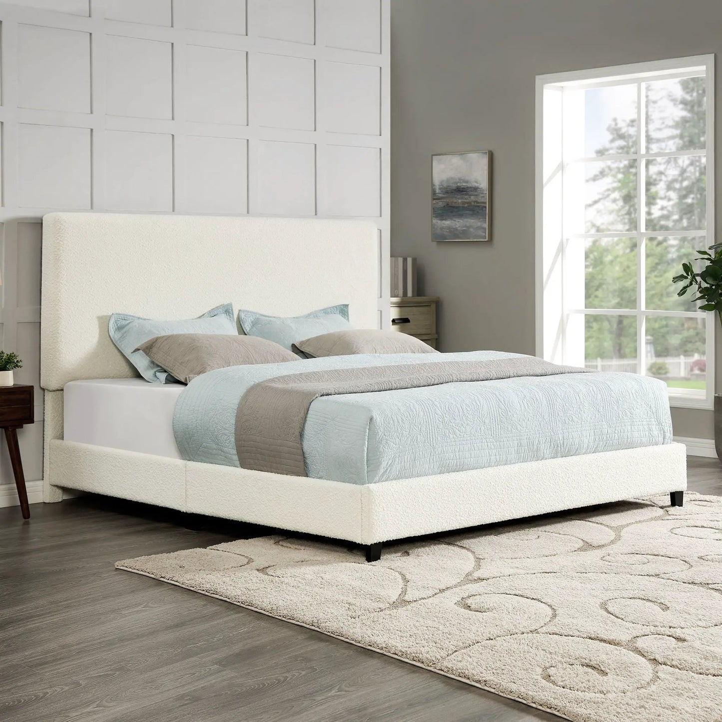 Platform bed with cream upholstered headboard and light blue bedding in a bright bedroom on Tampa Home & Garden Store