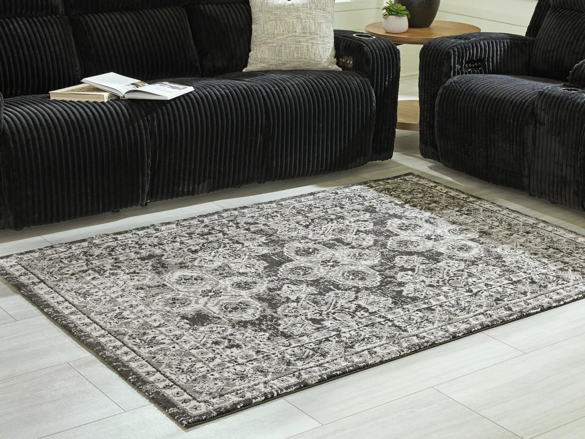 Glennisman Rug by Unique Piece Furniture in gray on light floor beside black corduroy seating on Tampa Home & Garden Store