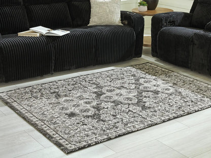 Glennisman Rug by Unique Piece Furniture in gray on light floor beside black corduroy seating on Tampa Home & Garden Store