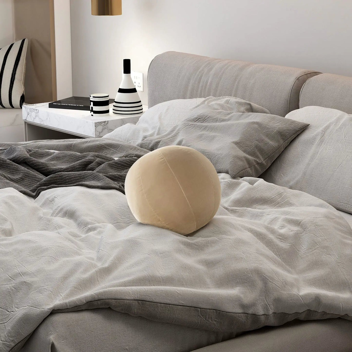 Pair of Luna Round Sphere Ball Throw Pillows on bed with gray bedding beside marble nightstand on Tampa Home & Garden Store