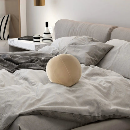 Pair of Luna Round Sphere Ball Throw Pillows on bed with gray bedding beside marble nightstand on Tampa Home & Garden Store