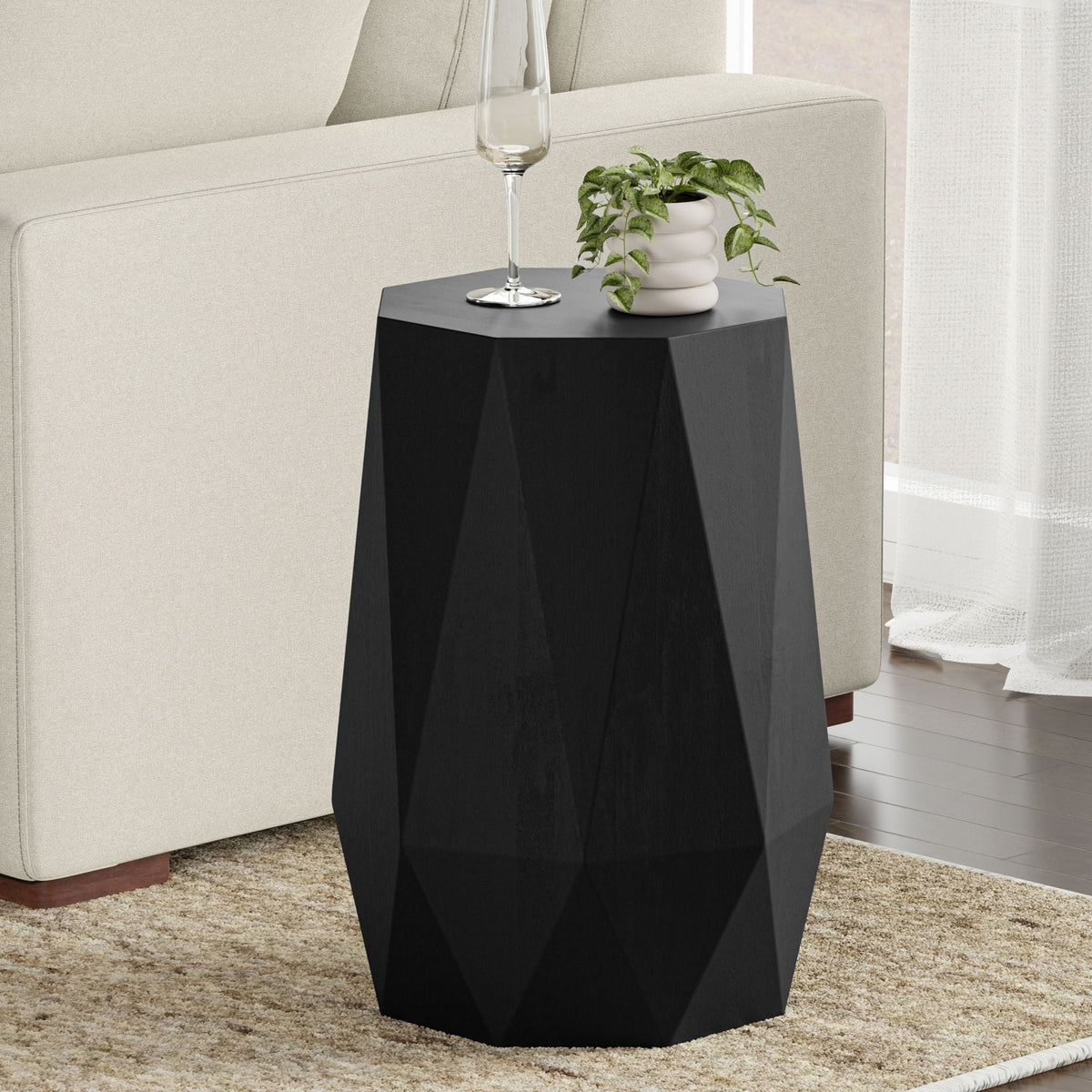 Solid acacia wood side table with sculpted faceted form in black finish beside sofa on Tampa Home & Garden Store