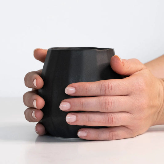 Ceramic stemless wine glass with a matte black finish held in hands on Tampa Home & Garden Store