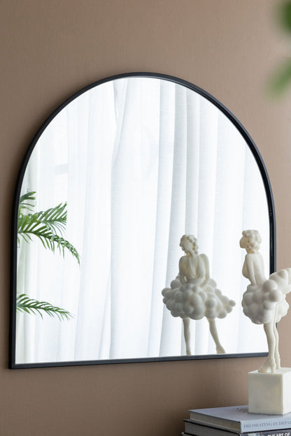 Arched mirror with black metal frame on beige wall, reflecting white curtains and plant on Tampa Home & Garden Store
