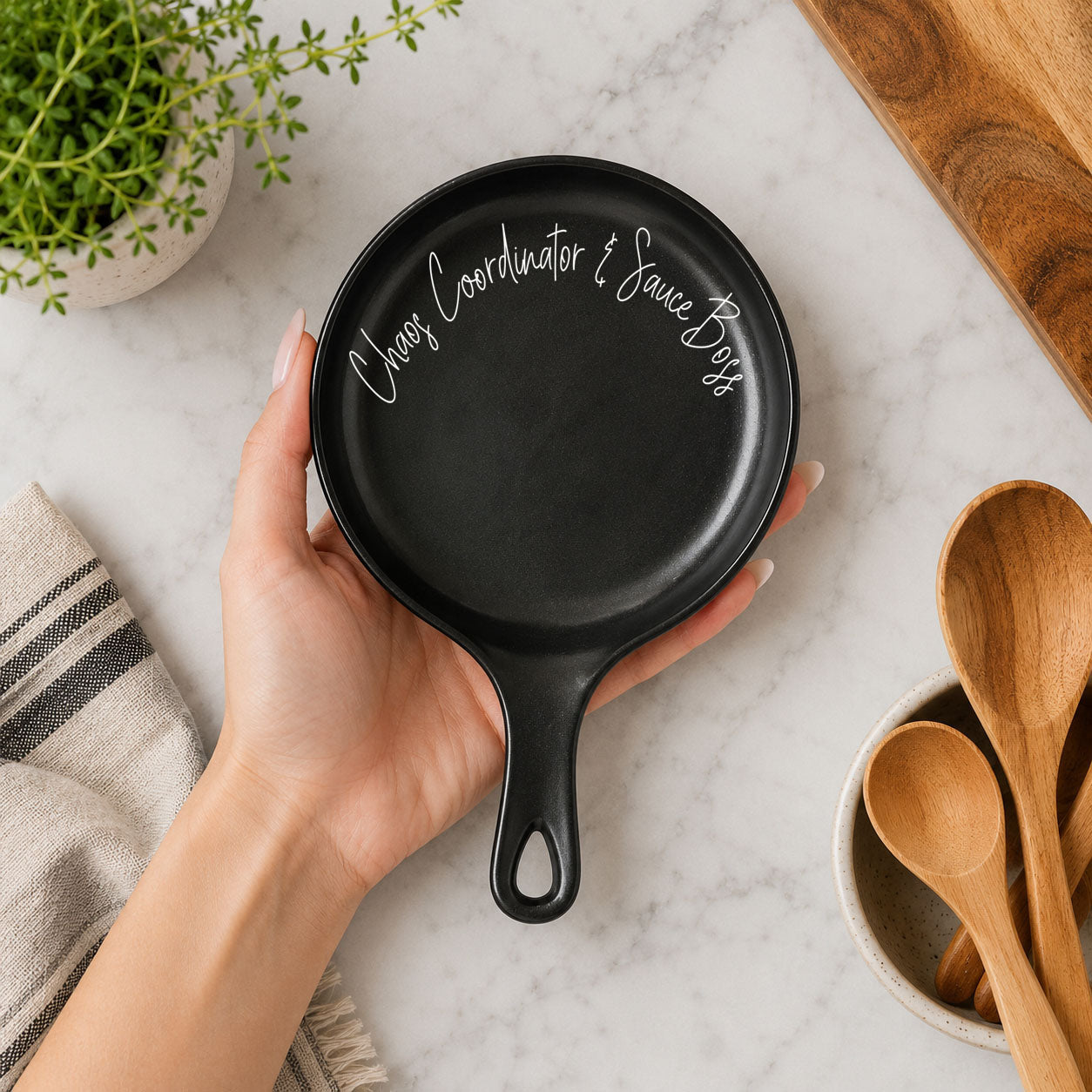 Black spoon rest with white script Chaos Coordinator & Sauce Boss held in hand on Tampa Home & Garden Store