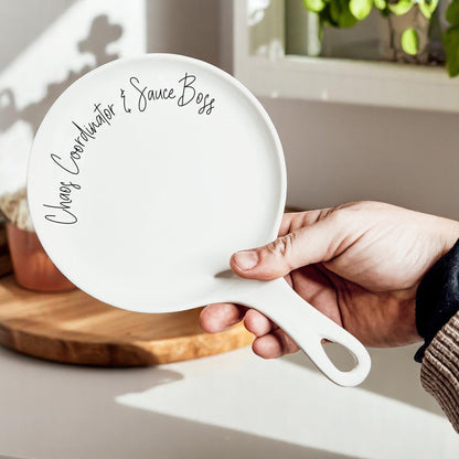 Spoon rest Chaos & Sauce Boss by Gia Roma, white ceramic with black cursive edge text on rim on Tampa Home & Garden Store