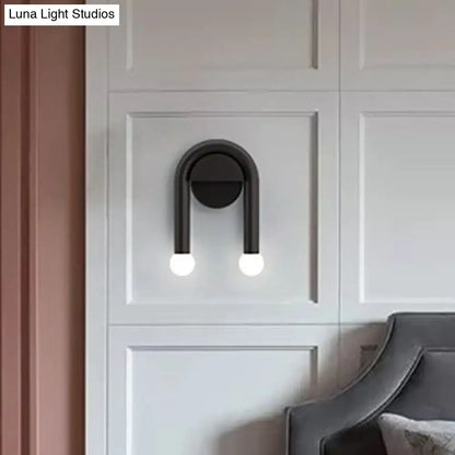 Black U-Shaped Wall Light by Decorbites, black metal fixture with two glowing bulbs on white paneled wall on Tampa Home & Garden Store
