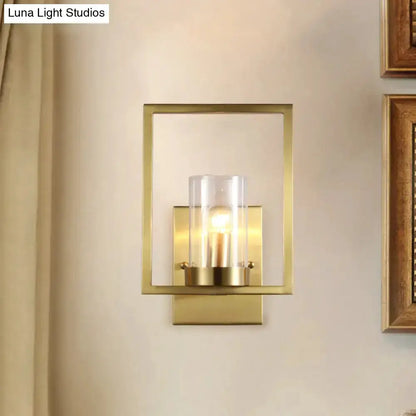 Contemporary brass wall light with clear glass cylinder inside a square frame on Tampa Home & Garden Store