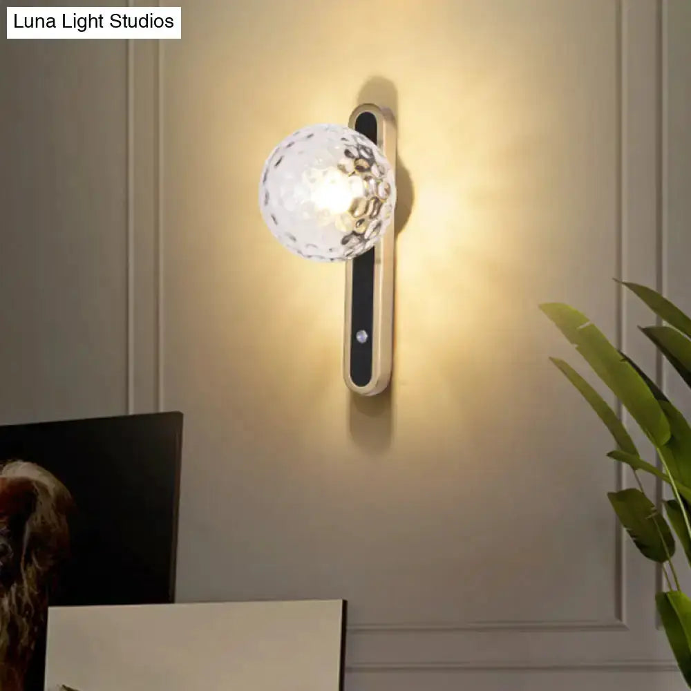 Contemporary clear glass wall lamp sconce with brass backplate and warm glow on Tampa Home & Garden Store