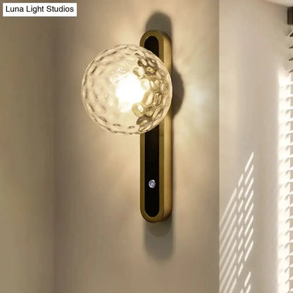 Contemporary clear glass globe wall lamp with brass mount and black panel, Decorbites sconce on Tampa Home & Garden Store