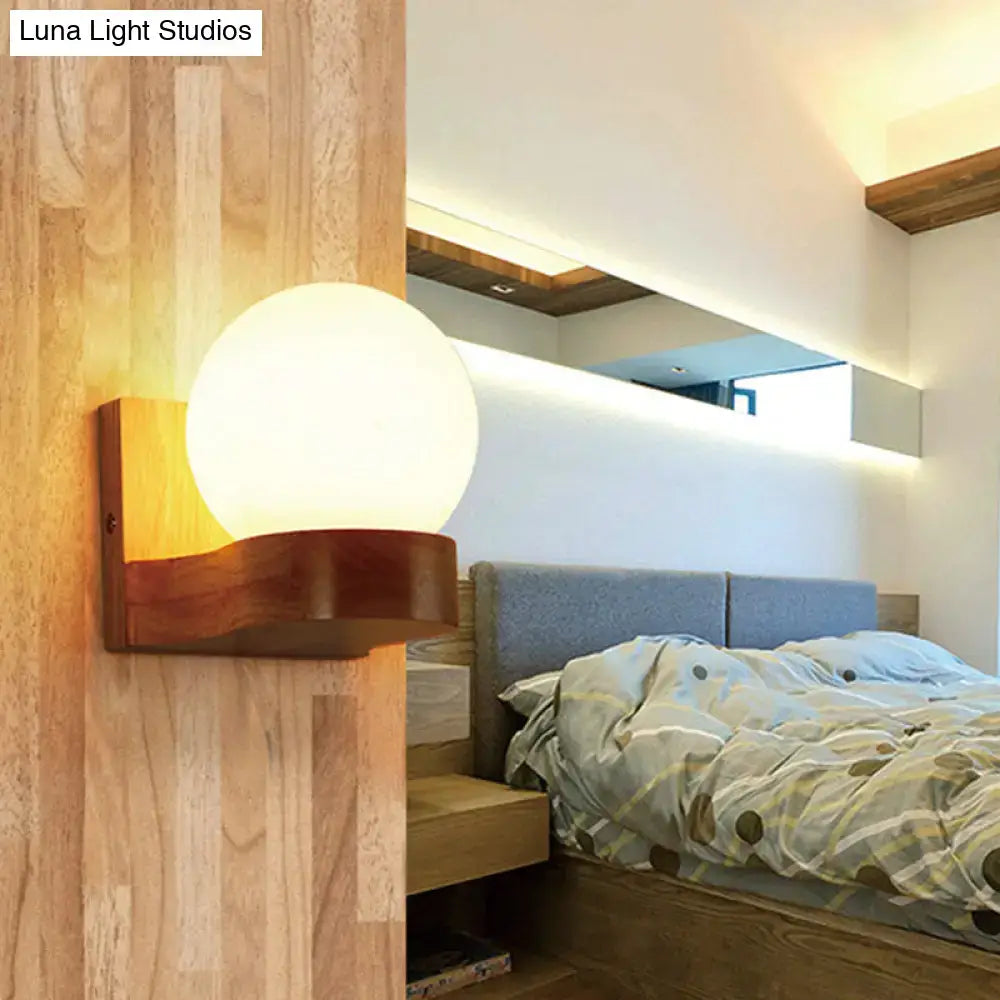 Cream glass wood sconce with round globe on a warm wooden mount by Decorbites in a modern bedroom on Tampa Home & Garden Store