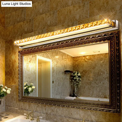 Contemporary crystal gold wall sconce with warm white LED above ornate bathroom mirror on Tampa Home & Garden Store