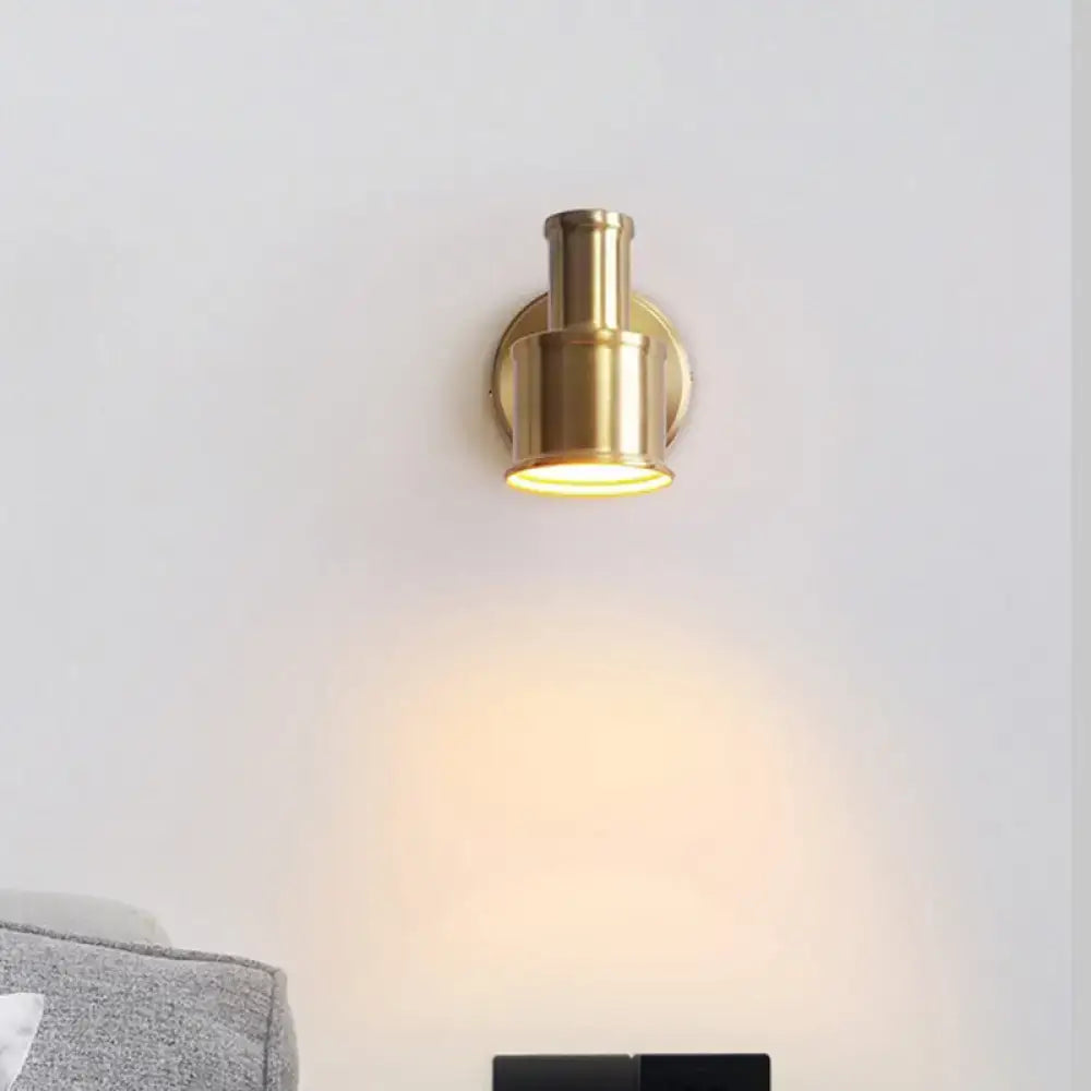 Gold cylinder wall sconce with round backplate in brass finish, wall-mounted warm downward light on Tampa Home & Garden Store