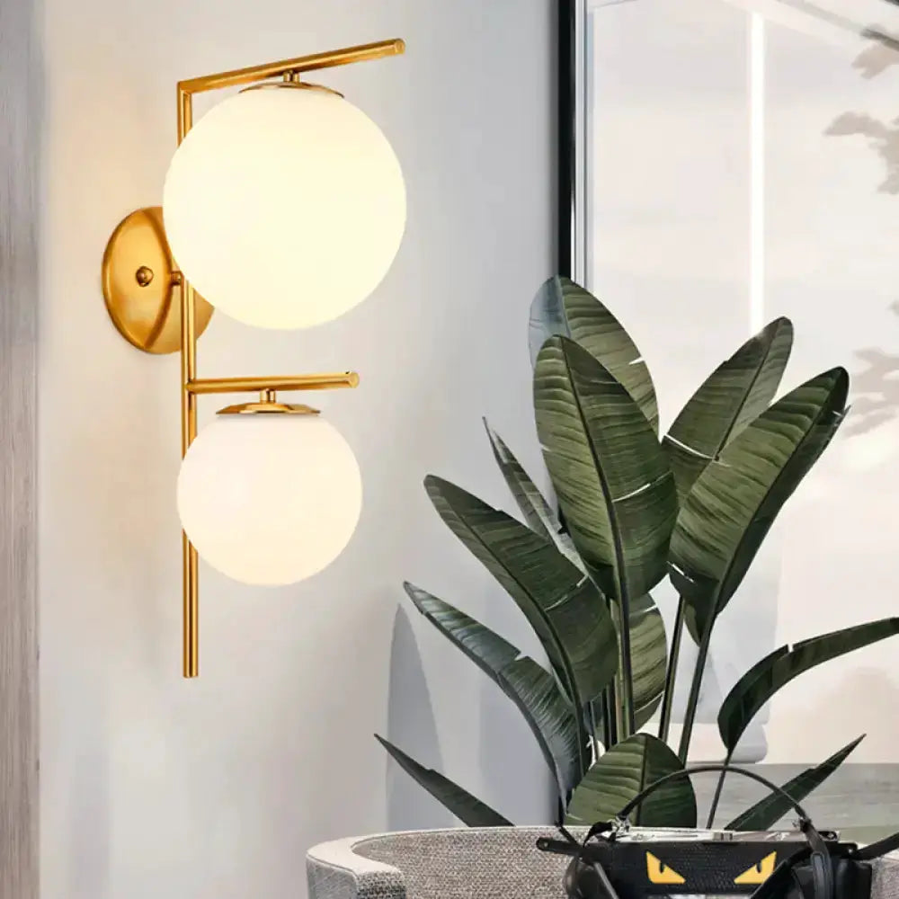 Contemporary gold and white double-sphere glass bedroom sconce with brass wall mount on Tampa Home & Garden Store