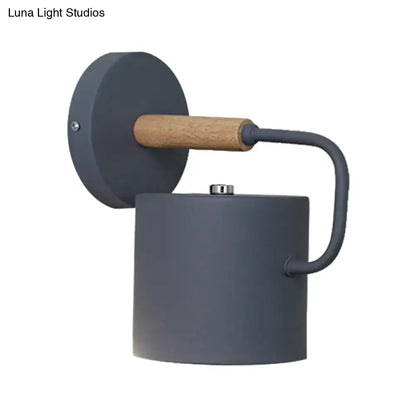Gray metal wall sconce with cylindrical body, curved arm, and natural wood accent on Tampa Home & Garden Store